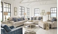 a living room filled with white furniture and lots of windows on top of the walls