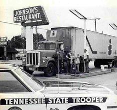 an old black and white photo of two men standing in front of a truck at a restaurant