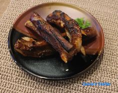 a plate with ribs and garnishes on it sitting on a table cloth