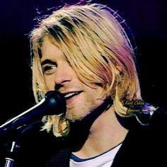 a man with long blonde hair singing into a microphone