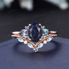 a ring with blue and white stones in it on top of a black cloth covered surface