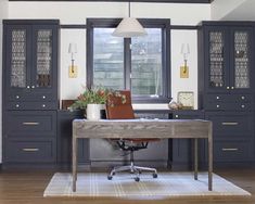 a home office with dark blue cabinets and leather chair