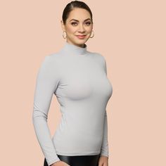 Indulge in the opulent coziness and effortless elegance of our newly updated mock neck. Featuring a sleek and refined neckline, it now comes in 10 stunning hues. Crafted from luxurious Italian 4 way stretch microfiber fabric, it delicately cascades over the figure and eliminates clinginess when layered with other garments. An essential piece for your autumn and winter collection, this top can be worn alone for a striking look or layered under sweaters or jackets. Elegant Mock Neck Top For Winter Layering, Sleek Solid Color High Neck Turtleneck, Sleek High Neck Turtleneck, Elegant Solid Long Sleeve Turtleneck, Elegant Long Sleeve Solid Turtleneck, Elegant Stretch Mock Neck Top For Winter, Elegant Winter Mock Neck Top With Stretch, Elegant High Stretch Tops With Thumbholes, Elegant Second-skin Long Sleeve Tops