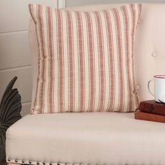 a coffee cup sitting on top of a white chair next to a stack of books