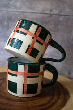 This listing is for a single, wheel-thrown, hand-glazed ceramic coffee or tea mug. Made with Laguna brand Dover White clay. The exterior has a hand-painted forest green and red checkered pattern that is completed with unglazed/exposed clay and a white-glazed interior. There is no foot on either of these mugs, so they sit flush against the surfaces they're set on. These mugs are lightweight and well-balanced, making it comfortable to hold in the hand. Please note that the greatest variance between these mugs is the handle -- please let me know if you prefer one over the other! All glazes are food-safe and pieces are dishwasher, microwave, and oven safe. Dimensions: 3" at the widest part of the opening (not including handle), 3" tall Capacity: up to 6oz All pieces are Cone 5 (mid-fired), mak Green Buffalo Plaid, Condo Inspiration, Painted Mug, Dover White, Red Checkered, Van Nuys, Gift Inspo, White Pottery, Stoneware Mugs