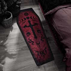 a red and black floor mat sitting on top of a wooden floor next to a bed