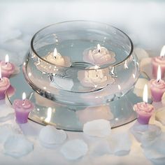 several candles are floating in a glass bowl