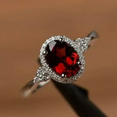 a red and white diamond ring sitting on top of a wooden table