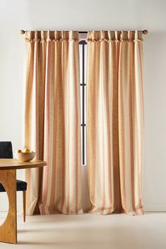 a dining room with a table and chairs next to a window covered in striped curtains