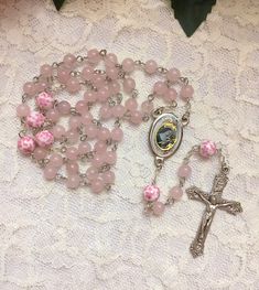 Handmade St. Rita of Cascia rosary beads made with 6mm pink Rose Quartz beads and 8mm ceramic pink & white floral beads. The center and crucifix are both made in Italy. Pink Rosary Aesthetic, Handmade Pink Rosary Bracelet With Round Beads, Pink Beaded Spiritual Rosary, Pink Beaded Rosary With Round Beads, Pink Beaded Spiritual Rosary Bracelet, Pink Rosary With 8mm Round Beads, Pink Beaded Rosary, Pink Spiritual Rosary Bracelet With 8mm Beads, Pink 8mm Bead Spiritual Rosary Bracelet