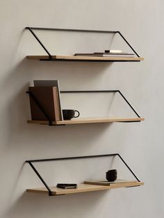 two shelves with books, coffee cup and notebooks on them against a white wall