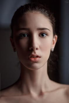 a beautiful young woman with blue eyes and no shirt on looking at the camera while standing in front of a window