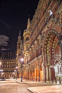 an old building is lit up at night with street lights and cobblestone streets