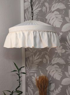 a white lamp hanging from a ceiling next to a plant