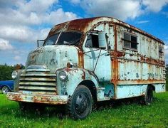 an old rusted out truck sitting in the grass