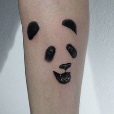 a black and white panda bear face tattoo on the right leg, with eyes closed