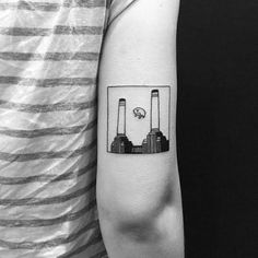 a man's arm with a black and white photo of two factories on it