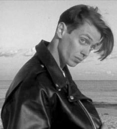 a black and white photo of a man in a leather jacket looking at the camera