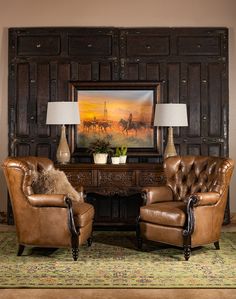 two brown leather chairs sitting in front of a painting