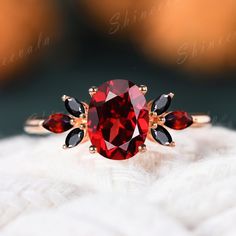 a close up view of a ring with a red stone and two black stones on it