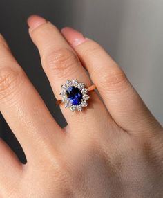 a woman's hand with a ring on it and a blue stone in the middle