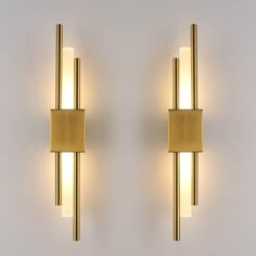 two lights that are next to each other on a white wall, one is gold and the other is silver