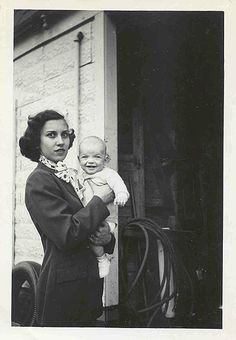 an old black and white photo of a woman holding a baby in her arms,