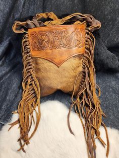 This bag sure is one of a kind and unique. featuring hair on hide and soft Kodiak this western style bag features hand-tied Fringe, bag was hand tooled in a classic western style leather smithing.  CUSTOM ITEMS ARE NON-REFUNDABLE. THERE ARE ZERO EXCEPTIONS TO THIS RULE.  MAKE SURE ALL MEASURMENTS, SIZING,DETAILS AND COLORS AND CLEARLY COMMMUNICATED WITH US. Hardware-Embellishments-Hides-Textures-Coloration may vary depending on what we have in stock to ensure quick and efficient service and deli Western Leather Bags With Concho Details, Hand Tooled Leather Bags For Rodeo, Western Style Brown Bag With Concho, Western Leather Bags For Rodeo, Bohemian Brown Bags With Concho, Hand Tooled Brown Bags For Rodeo, Hand Tooled Brown Bag For Rodeo, Western Bags With Concho Detail, Brown Hand Tooled Bag For Rodeo