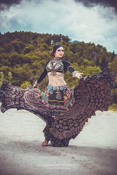 a woman is dancing on the beach with trees in the background