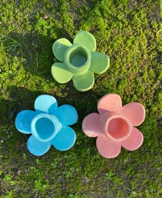 three flower shaped bowls sitting in the grass