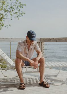 Male model sitting on a beach chair wearing sandals, shorts, a button up shirt and embroidered Lake Michigan dad hat. Casual Cotton Baseball Cap For Beach, Casual Cotton Beach Baseball Cap, Casual Cotton Hats For Vacation, Casual Denim Dad Hat, Casual Cotton Baseball Cap For Summer, Casual Denim Baseball Cap For Spring, Casual Adjustable Baseball Cap For Summer, Casual Adjustable Summer Baseball Cap, Classic Baseball Cap For Summer