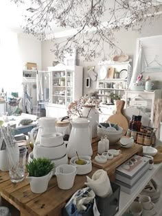 a room filled with lots of white dishes and cups on top of a wooden table