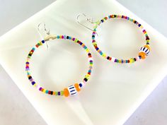 Bright multicolored African beads, Czech beads and seed beads are beaded onto 40mm silver plated hoop dangles and secured with permanent adhesive. They are secured to sterling silver French wires. Brighten up your day with these fun swingy earrings. Sterling Silver Multicolor Beaded Bracelets, Playful Multicolor Hoop Jewelry, Colorful Beaded Earrings In Sterling Silver, Colorful Round Beaded Sterling Silver Earrings, Playful Handmade Hoop Jewelry, Colorful Sterling Silver Beaded Earrings, Sterling Silver Beaded Earrings With Colorful Beads, Handmade Multicolor Heishi Beads Hoop Earrings, Handmade Multicolor Hoop Earrings With Heishi Beads