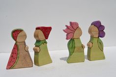 three wooden figurines in different colors and sizes, one with a flower on its head