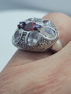 This is a vintage red garnet with purple amethist sidestones, surrounded by cubic zirconia ring set in 925 sterling silver. We have in size 7, this can be sized to your specification, please message us to discuss sizing your ring or engraving options. All of our jewelry is hand polished and shipped to you in a stylish gift box. We are happy to gift wrap for you. It is important to us that each customer be thrilled with their purchase. We are grateful for thousands of positive reviews. Formal Rings With Cubic Zirconia Stones, Formal Cubic Zirconia Rings With Stones, Silver Garnet Crystal Ring For Anniversary, Silver Marquise Ruby Ring For Anniversary, Silver Marquise Multi-stone Diamond Ring, Silver Crystal Ring With Diamond Stones, Classic Multi-stone Cluster Ring With Cubic Zirconia, Silver Crystal Ring With Diamonds, Marquise Multi-stone Cubic Zirconia Rings