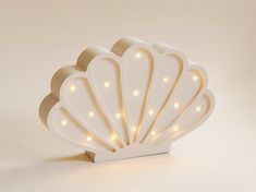 a white shell shaped light up decoration with lights on it's sides and the shape of a scallop