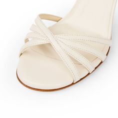 Nadine in milk is a showstopper worthy of your attention. Designed and made in Italy, this classic style has multi-band strap across the toes and a slim sandal back. The front straps design can accommodate wider feet, or bunions if needed. The shoe is finished with a subtle signature brilliant adornment on the left heel. With a soft gel padding, you are comfortable from the very first wear. Leather construction with leather lining & sole Wraparound fastening, can be worn around ankle or under in Classic Evening Sandals With Penny Strap, Fitted Slingback Sandals With Heel And Single Toe Strap, Summer Cream Kitten Heels With Ankle Strap, Cream Ankle Strap Kitten Heels For Summer, Classic Cream Ankle Strap Sandals, Classic Strappy Leather Heels, Classic Leather Strappy Heels, Elegant White Kitten Heels With Single Toe Strap, Classic Single Toe Strap Kitten Heels For Summer