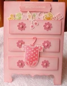 a pink dresser with flowers on it and a baby's bib hanging from the drawer