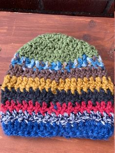 a multicolored crocheted hat sitting on top of a wooden table