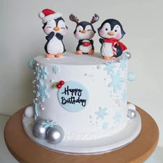 a birthday cake decorated with penguins and snowflakes