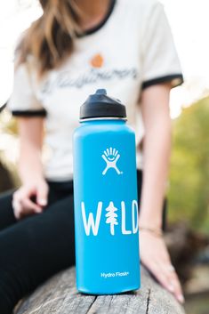 a blue water bottle sitting on top of a wooden table next to a woman's legs