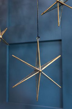 three gold stars hanging from strings against a blue wall