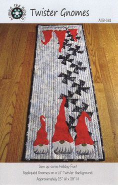 a quilted table runner with red and black gnomes on it, sitting on a wooden floor