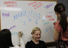 two girls writing on a whiteboard with markers