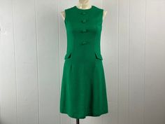 "Vintage 1960s Mod dress. Made of green knit linen or cotton rayon. Has faux button front and two faux hip pockets. Back zipper. Unbranded. About a size small/medium. Actual measurements are:   34\" around the bust  30\" around the waist  34\" around the hips   13.5\" shoulder to shoulder   38\" overall length In very good condition." Green Mod Cotton Dress, Retro Green Dress With Buttons, Vintage Green Dress For Work, 70s Mode, 1960s Mod Dress, 60s And 70s Fashion, 1960s Dress, Mod Vintage, 1960s Mod