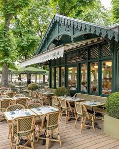 an outdoor restaurant with tables and chairs on the wooden flooring outside, surrounded by trees