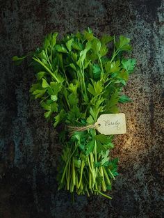 fresh green parsley on a rusty surface with a tag that says,'herbs '