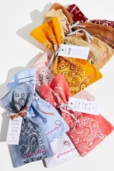 a pile of different colored scarves on top of each other with tags attached to them