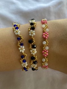 three different bracelets on someone's arm, one with beads and the other with flowers