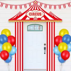 a circus tent with balloons and streamers in front of the door for a birthday party